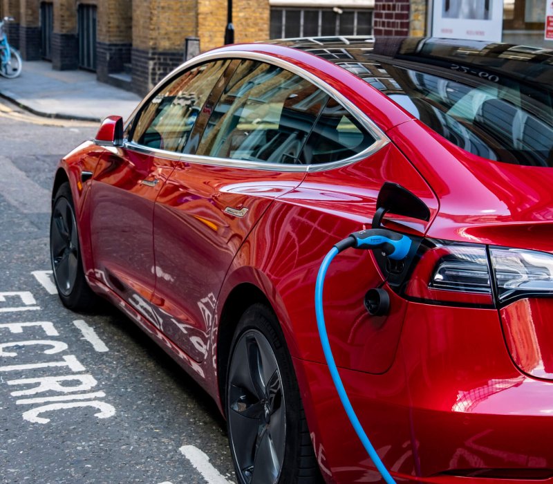 London, June 2020: A red Tesla Model 3 parked and charging in a designated charging bay in central London